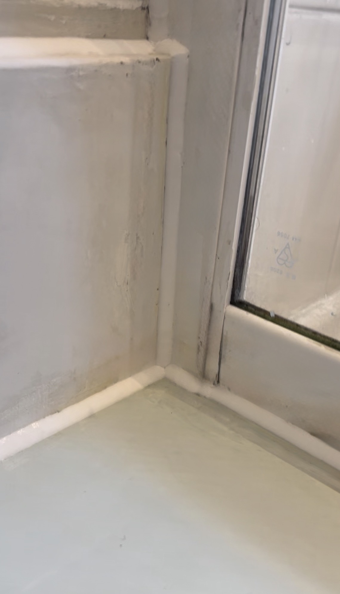 The same shower enclosure after full silicone removal and a clean white reseal