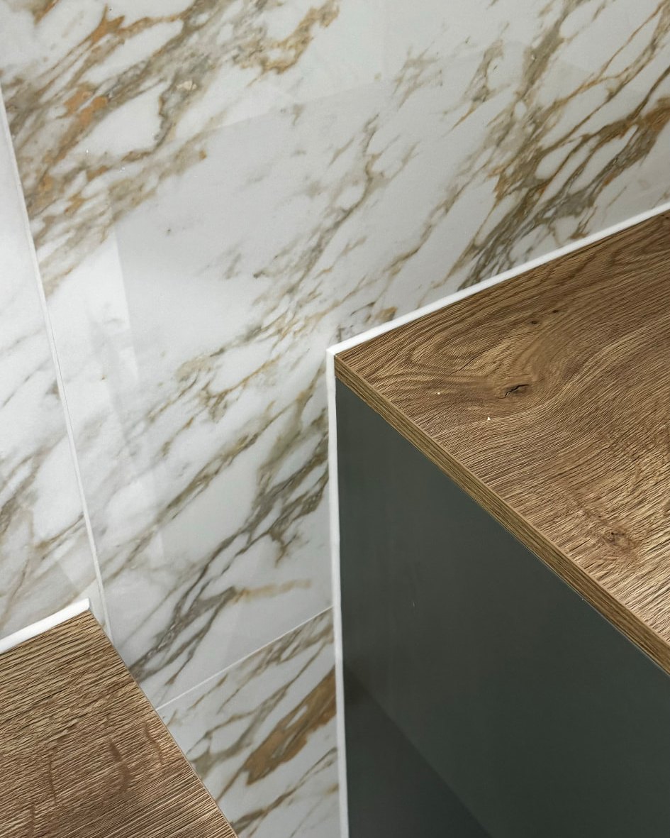 Fine white silicone corner joint where marble-effect bathroom tiling meets a fitted vanity unit